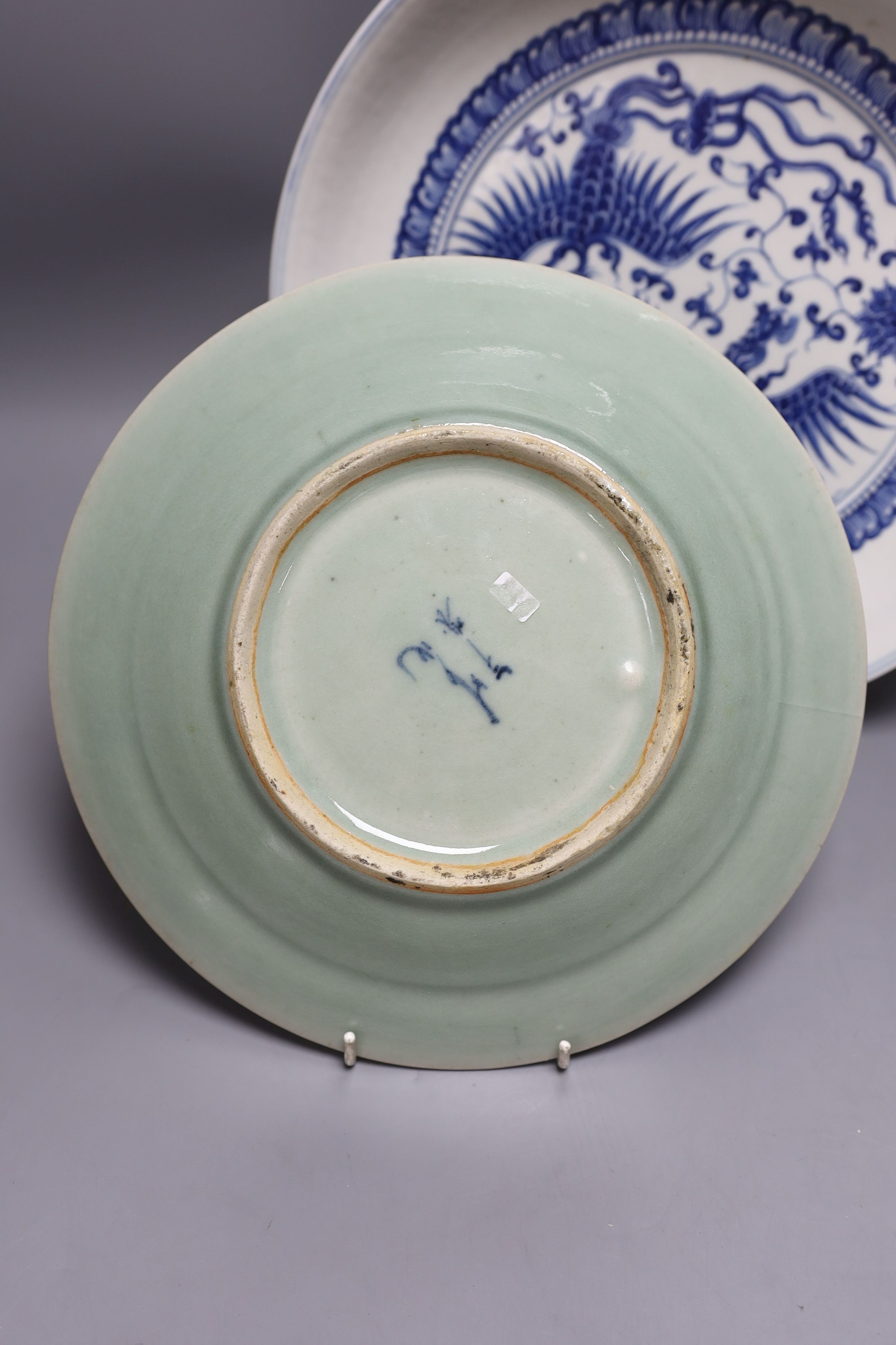 A 19th century Chinese blue and white celadon ground charger, marked to base, together with another blue and white Chinese charger (2)